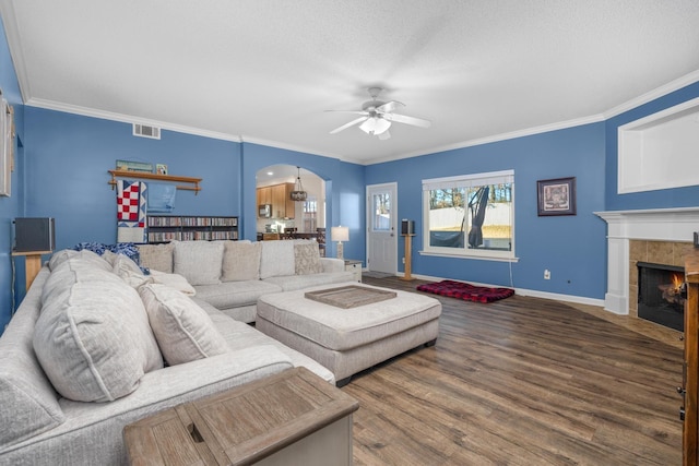 living room featuring crown molding, a textured ceiling, ceiling fan, a fireplace, and hardwood / wood-style floors