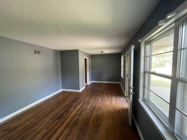 empty room with dark hardwood / wood-style flooring and a wealth of natural light