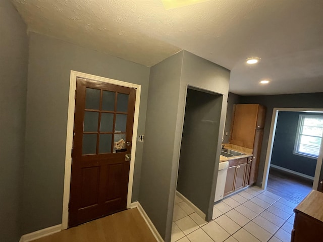 kitchen with dishwasher, light tile patterned floors, a textured ceiling, and sink