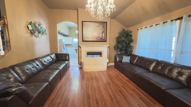 living room featuring hardwood / wood-style flooring, vaulted ceiling, a fireplace, and a chandelier