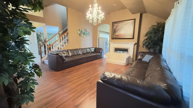 living room with hardwood / wood-style flooring, lofted ceiling, and a notable chandelier