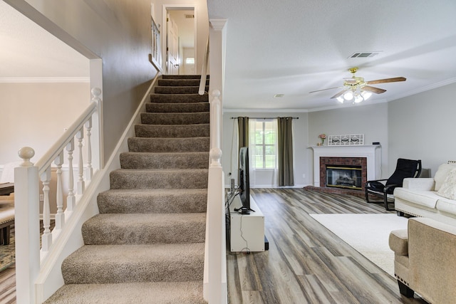 stairway featuring ceiling fan, ornamental molding, and hardwood / wood-style flooring