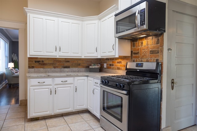 kitchen featuring light tile patterned flooring, white cabinetry, appliances with stainless steel finishes, and tasteful backsplash