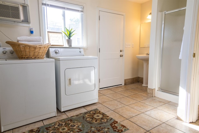 laundry area with a wall mounted AC, light tile patterned floors, washer and clothes dryer, and sink