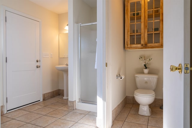 bathroom featuring tile patterned flooring, a shower with door, and toilet