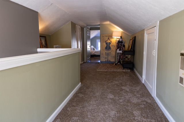 hall with dark colored carpet, a textured ceiling, and lofted ceiling