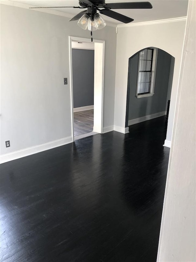 empty room featuring crown molding, ceiling fan, and dark wood-type flooring