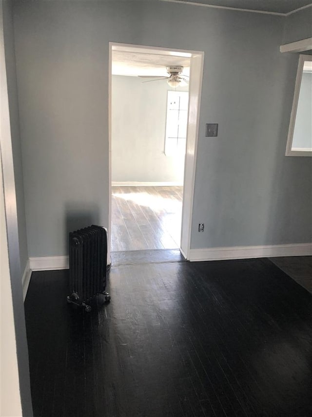 spare room with ceiling fan, dark hardwood / wood-style flooring, and radiator heating unit