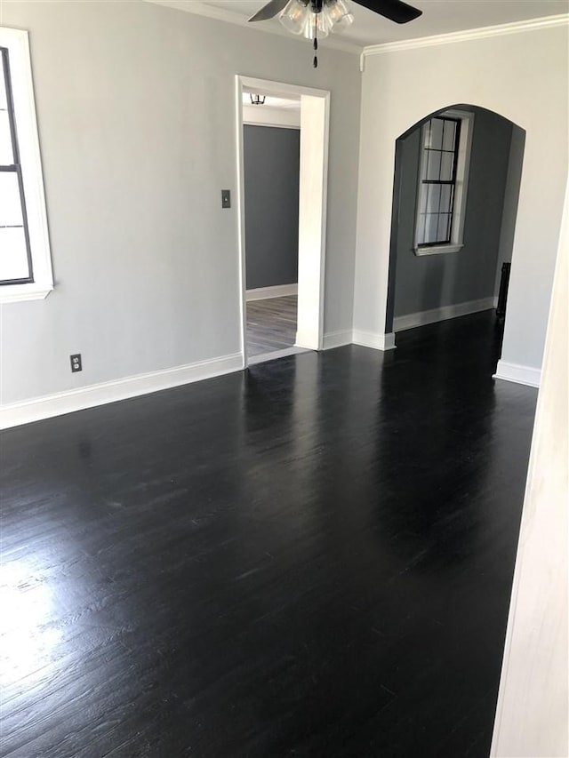 empty room with dark wood-type flooring, ceiling fan, and ornamental molding