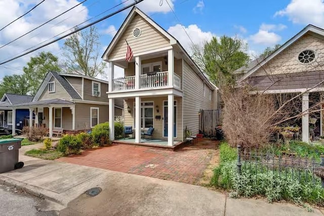 back of property featuring covered porch and a balcony