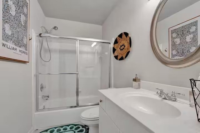 full bathroom featuring vanity, enclosed tub / shower combo, and toilet