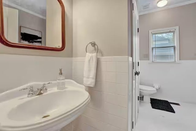 bathroom with sink, tile walls, and toilet