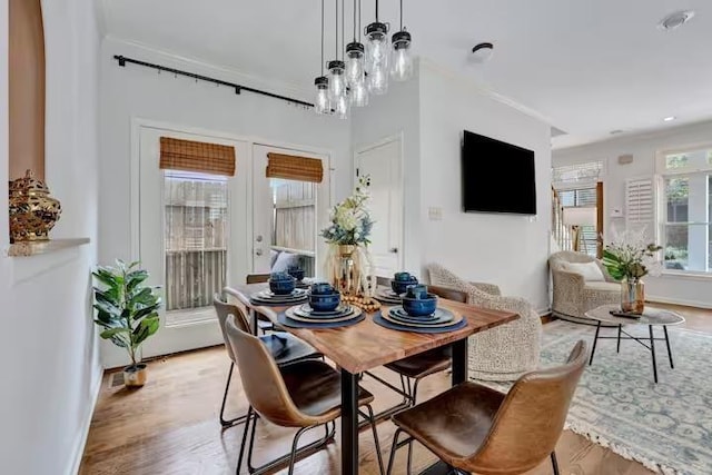 dining space featuring french doors, an inviting chandelier, light hardwood / wood-style flooring, and crown molding