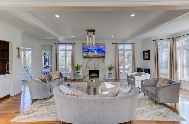 living room with a fireplace, ornamental molding, and light wood-type flooring