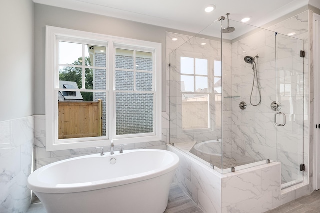 bathroom with hardwood / wood-style flooring, separate shower and tub, and tile walls