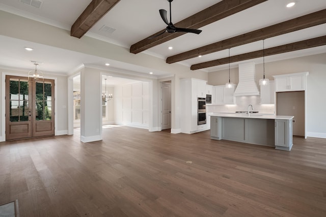 unfurnished living room featuring beamed ceiling, sink, dark hardwood / wood-style floors, and ceiling fan with notable chandelier