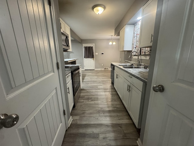 kitchen with pendant lighting, sink, appliances with stainless steel finishes, dark hardwood / wood-style flooring, and white cabinetry