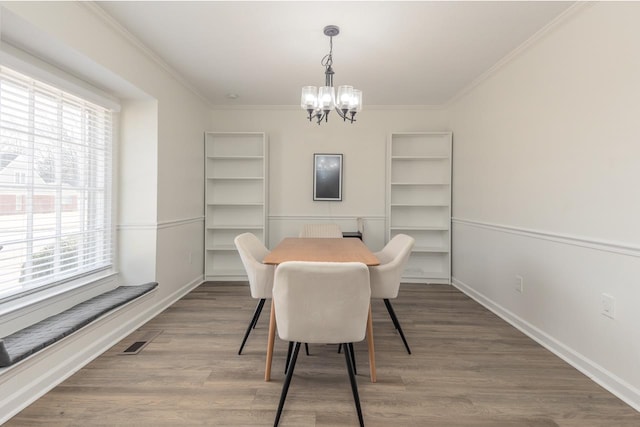 dining space with plenty of natural light, hardwood / wood-style floors, ornamental molding, and an inviting chandelier