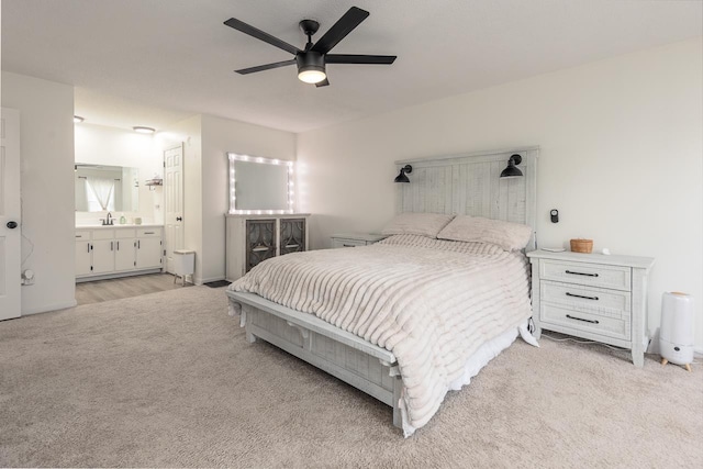 bedroom with ceiling fan, light carpet, sink, and ensuite bathroom