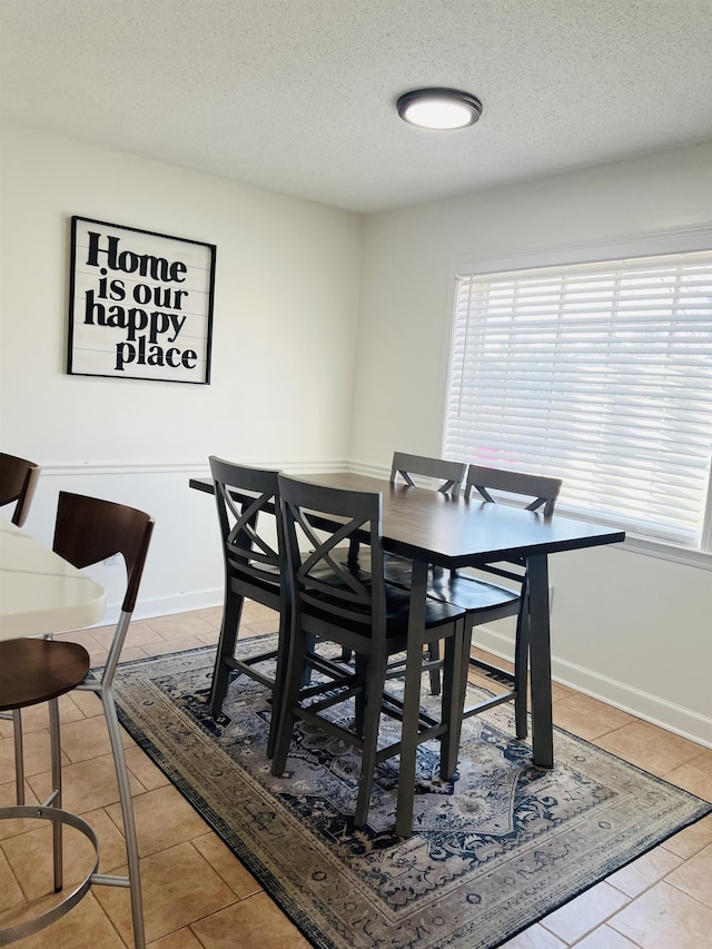 dining space featuring light tile patterned floors, a wealth of natural light, and a textured ceiling