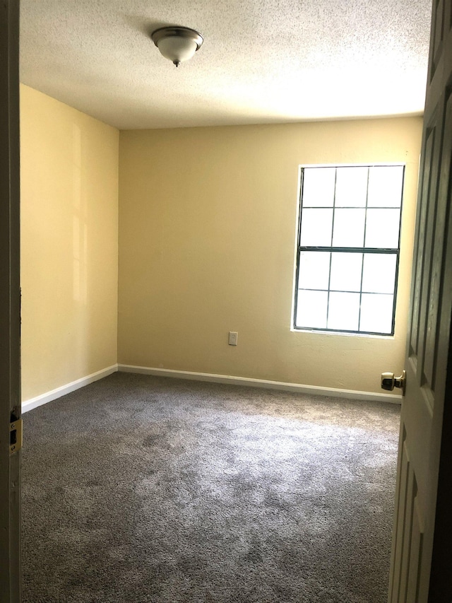 carpeted empty room featuring a textured ceiling