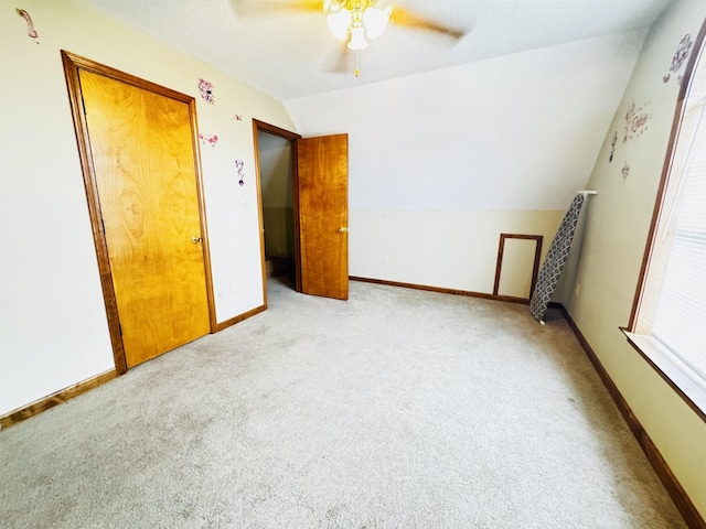 unfurnished bedroom featuring light colored carpet, ceiling fan, and lofted ceiling