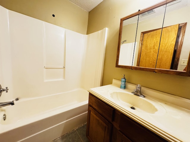 bathroom with tile patterned floors, vanity, bathing tub / shower combination, and a textured ceiling