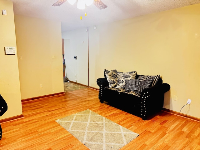 sitting room with ceiling fan and wood-type flooring