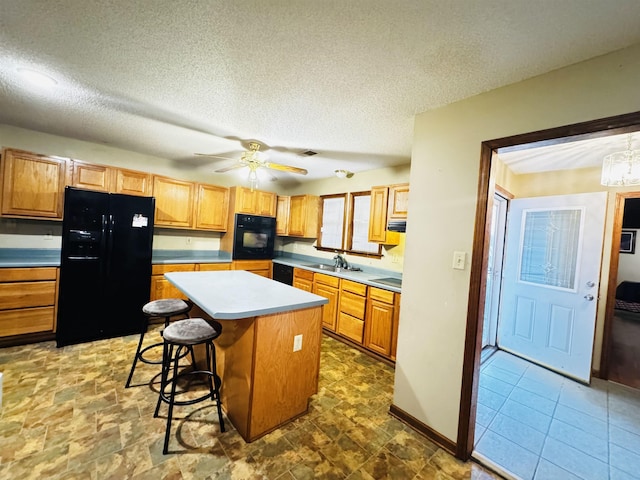 kitchen featuring sink, a textured ceiling, a kitchen bar, a kitchen island, and black appliances