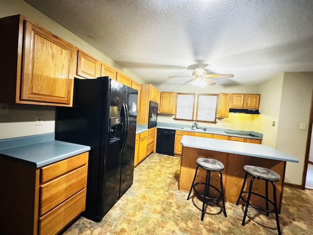 kitchen with ceiling fan, sink, a center island, a kitchen bar, and black appliances