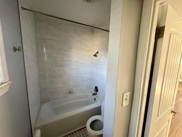 bathroom featuring tub / shower combination and toilet