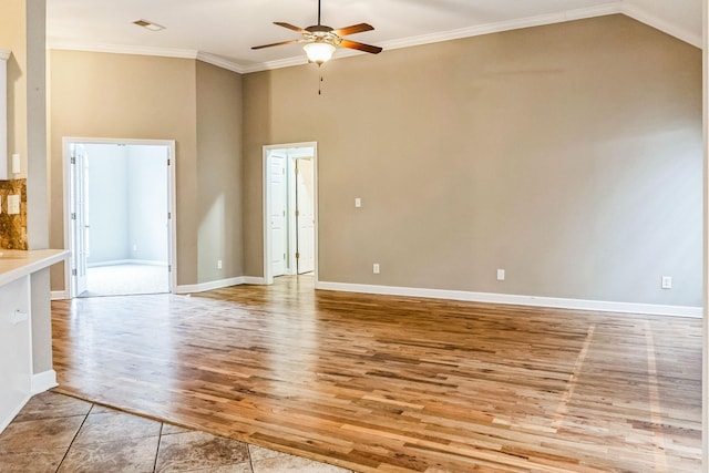 unfurnished living room with crown molding, ceiling fan, light tile patterned flooring, and a high ceiling