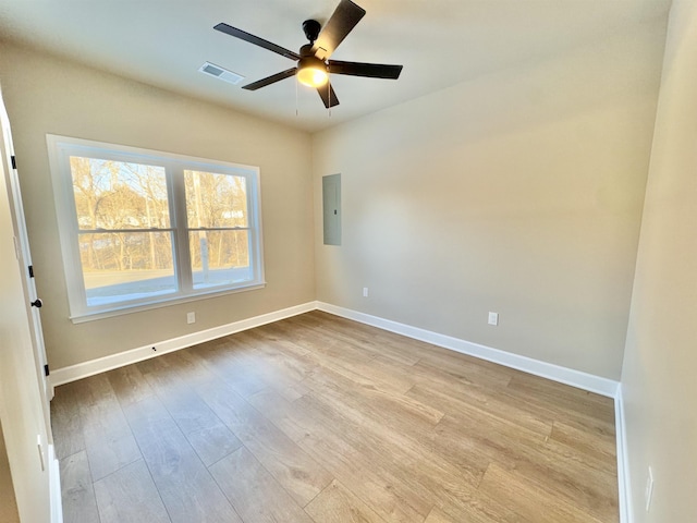 unfurnished room featuring baseboards, electric panel, visible vents, and wood finished floors