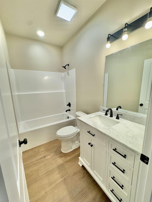 full bathroom featuring washtub / shower combination, vanity, wood finished floors, and toilet