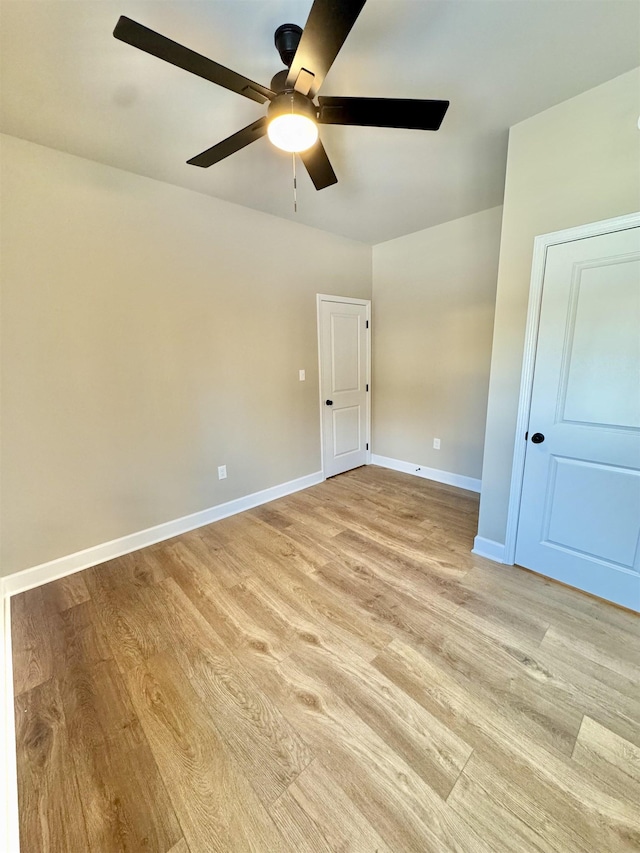 spare room with light wood-type flooring, ceiling fan, and baseboards