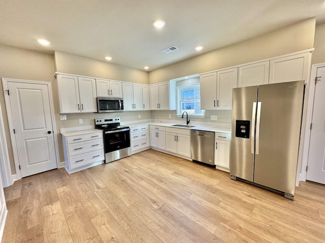 kitchen featuring white cabinets, sink, light wood-type flooring, and stainless steel appliances