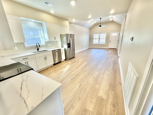 kitchen featuring visible vents, appliances with stainless steel finishes, vaulted ceiling, a sink, and light wood-type flooring