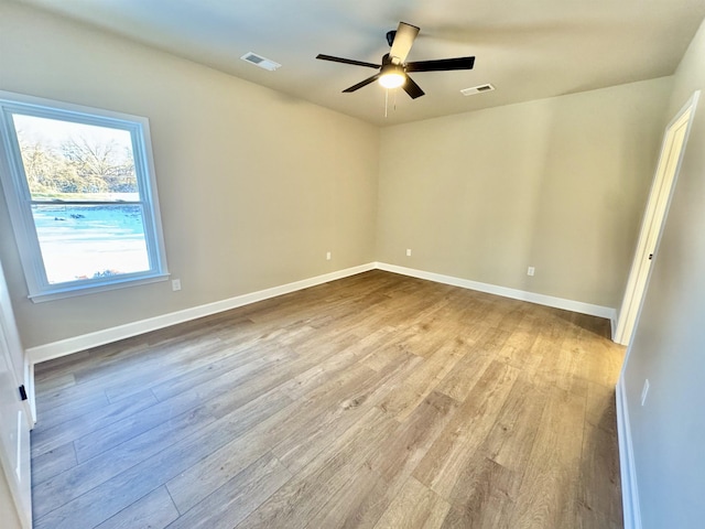 spare room featuring ceiling fan, wood finished floors, visible vents, and baseboards