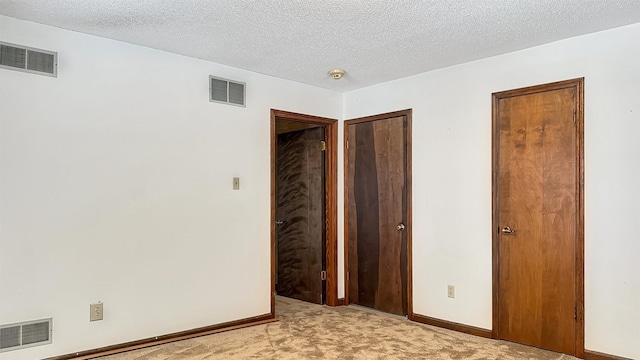 unfurnished bedroom featuring a textured ceiling and light carpet