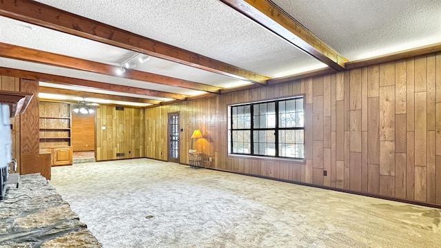 interior space with ceiling fan, rail lighting, a textured ceiling, wooden walls, and carpet