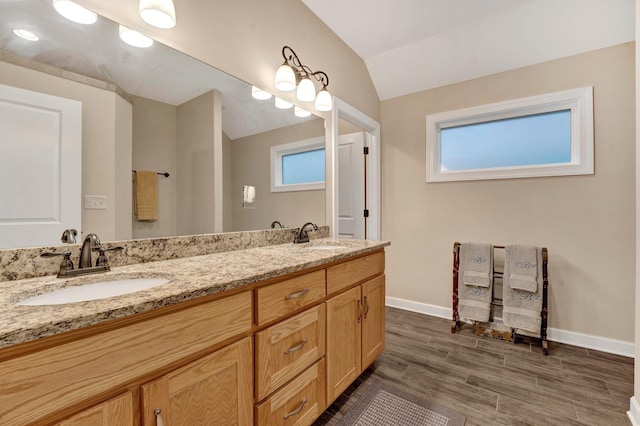 bathroom with a wealth of natural light, vanity, and vaulted ceiling