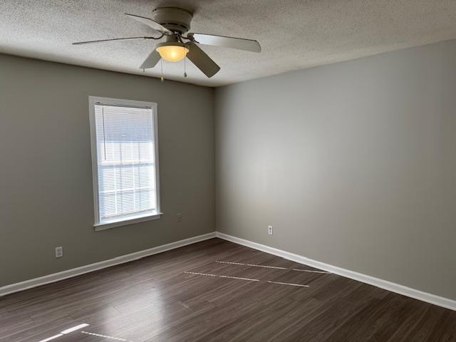 unfurnished room with a textured ceiling, ceiling fan, and dark wood-type flooring