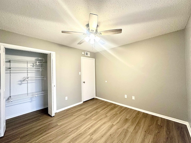 unfurnished bedroom featuring ceiling fan, a closet, a textured ceiling, and hardwood / wood-style flooring