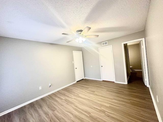 unfurnished bedroom featuring ceiling fan, a closet, a textured ceiling, and hardwood / wood-style flooring