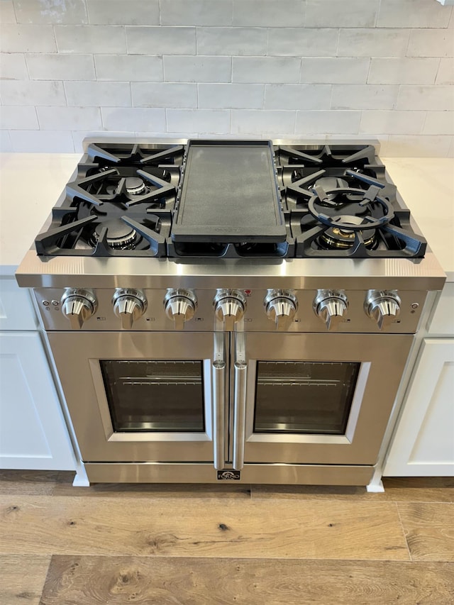 room details with white cabinets, tasteful backsplash, and high end stainless steel range