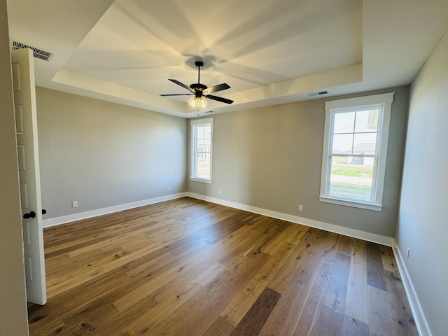 spare room with wood-type flooring, ceiling fan, and a tray ceiling