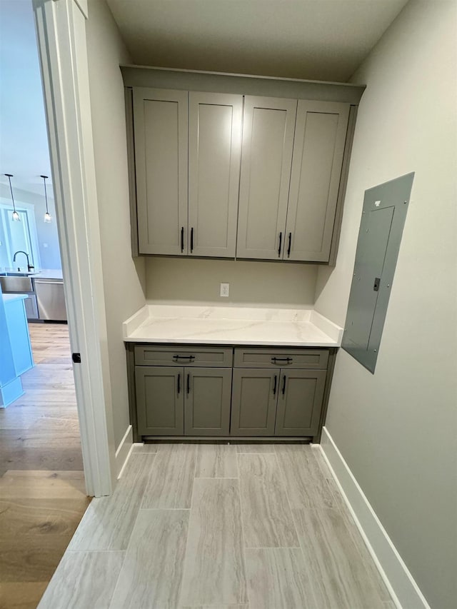 interior space with sink, electric panel, and gray cabinetry