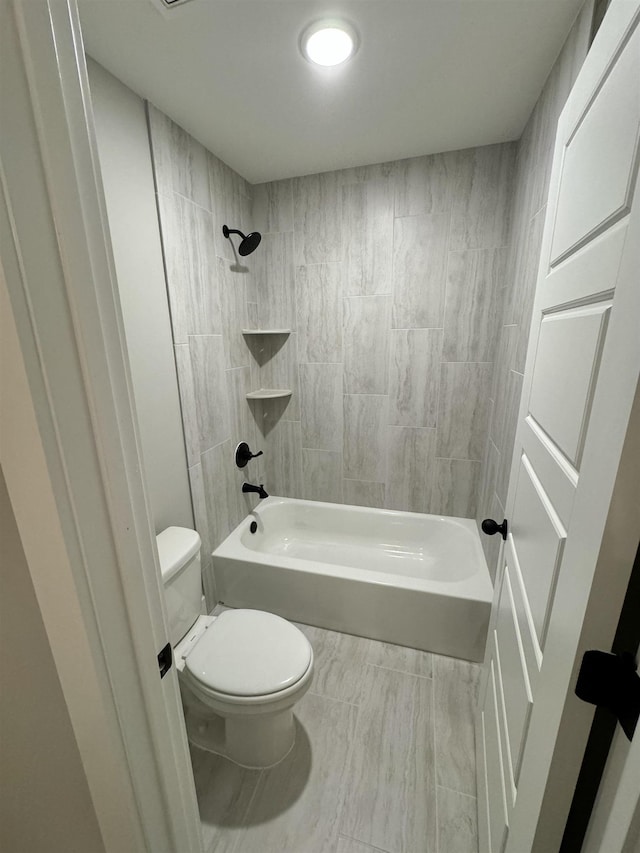 bathroom with toilet and tiled shower / bath