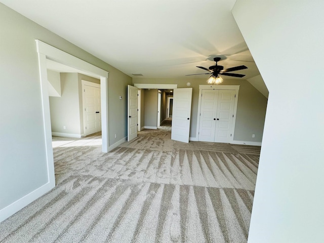 unfurnished living room featuring ceiling fan, light colored carpet, and lofted ceiling