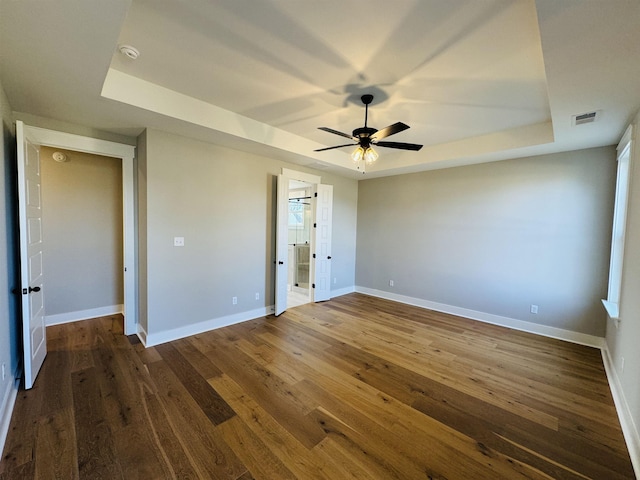 unfurnished bedroom with ceiling fan, a raised ceiling, and dark hardwood / wood-style floors